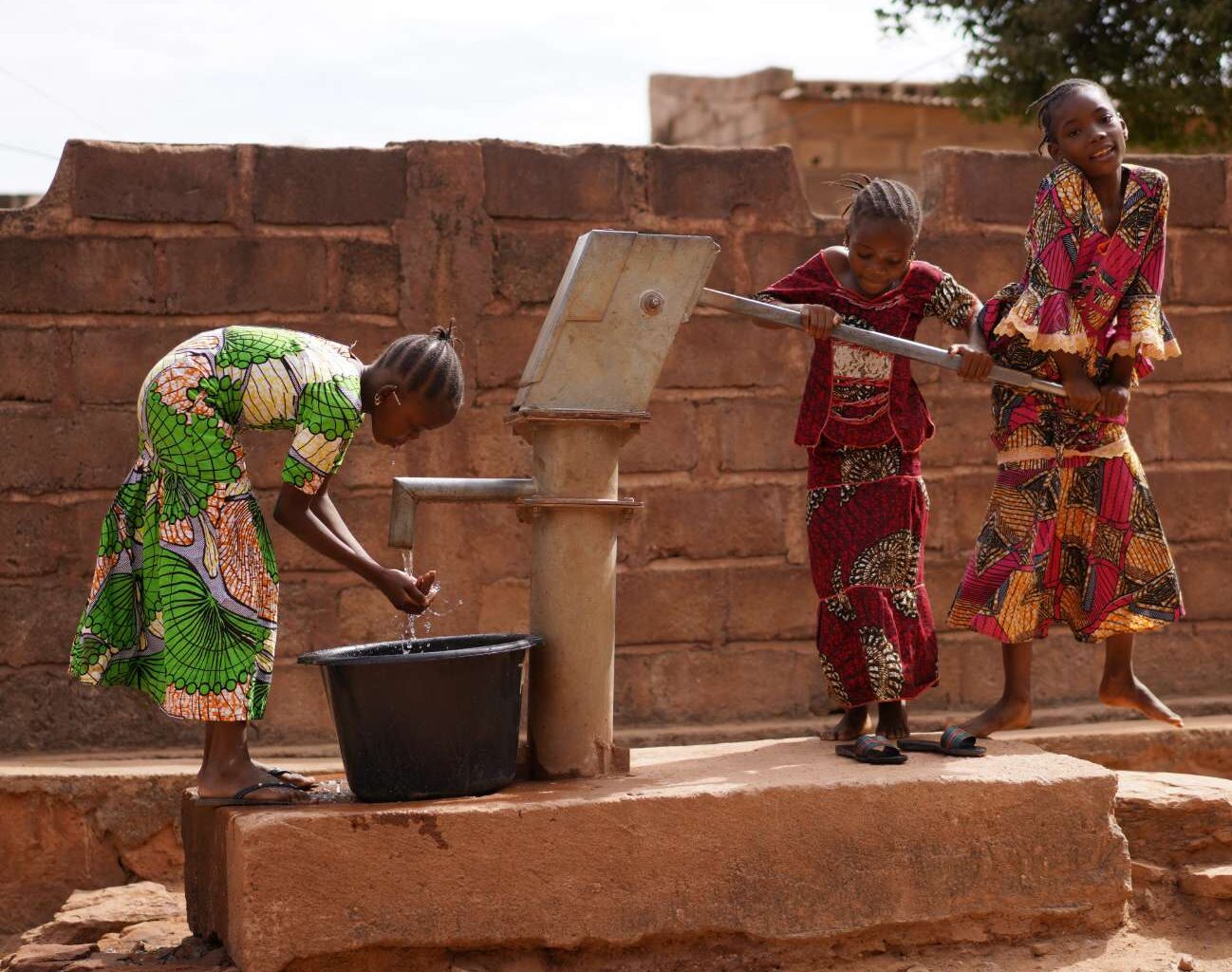 three women around a potable water tap